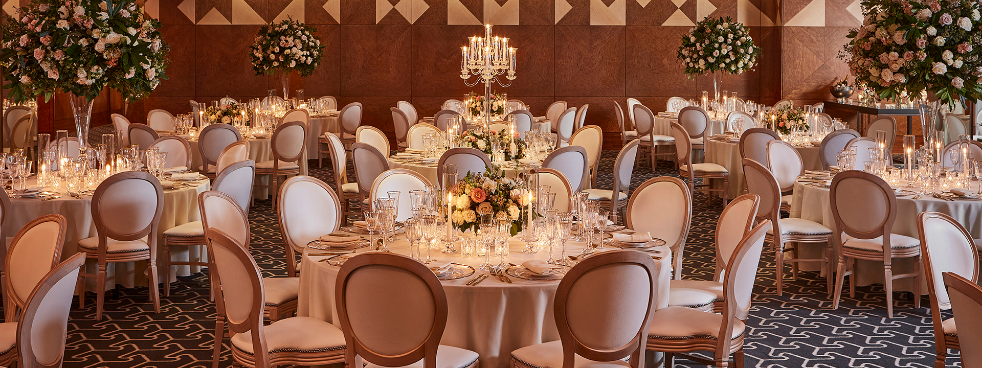 Ballroom set up for a private event with tables, chairs and flower arrangement.