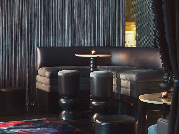 Low blue bar stools around tables in front of a blue fringed curtain in the Blue Bar glass pavilion