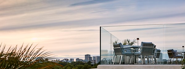 The rooftop pool and bar at The Berkeley, with a table and chairs on a terrace with a view on Hyde Park and the sun coming down.